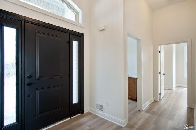 foyer featuring light wood-type flooring and a towering ceiling