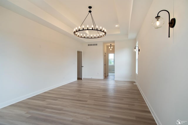 unfurnished dining area featuring wood-type flooring and a notable chandelier