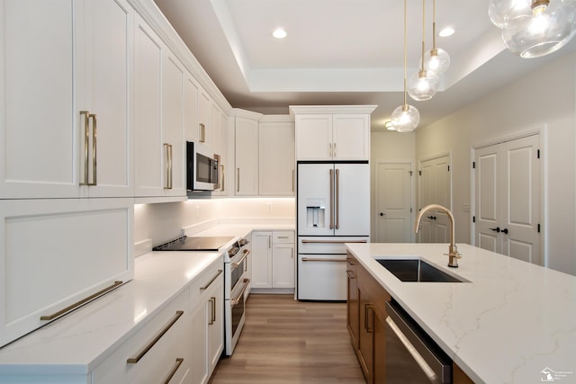 kitchen with sink, stainless steel appliances, light stone counters, decorative light fixtures, and white cabinets