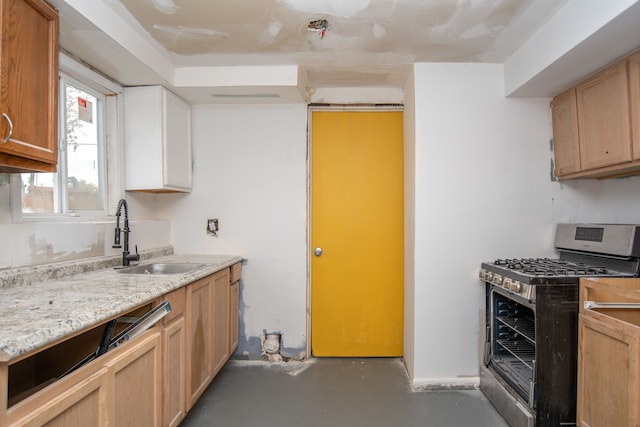 kitchen featuring light stone countertops, stainless steel gas stove, and sink