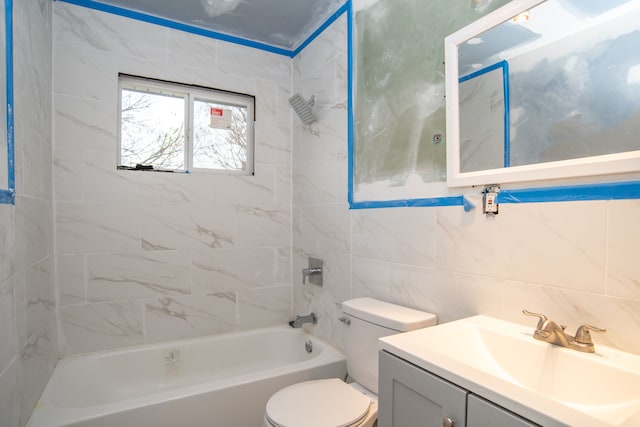 full bathroom with tile walls, vanity, tiled shower / bath combo, and toilet