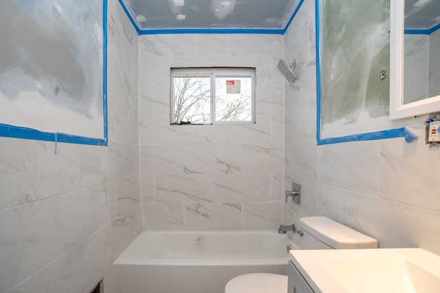 full bathroom with vanity, toilet, tiled shower / bath, and tile walls