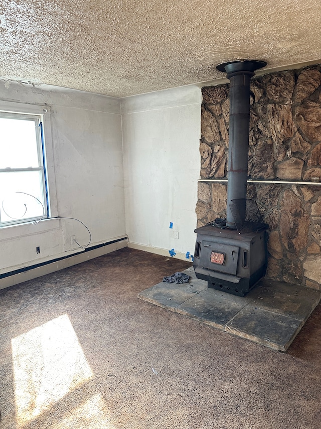 unfurnished living room with a wood stove, a textured ceiling, and dark colored carpet