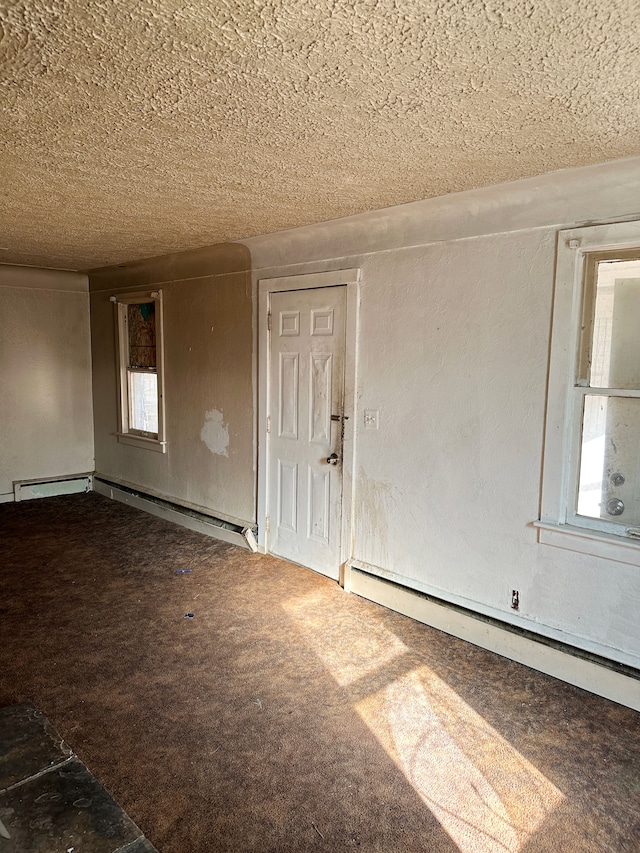 carpeted spare room with a textured ceiling and a baseboard heating unit