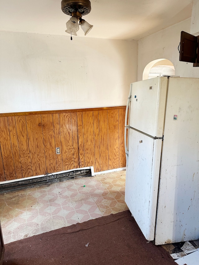 kitchen with wooden walls, ceiling fan, and white refrigerator