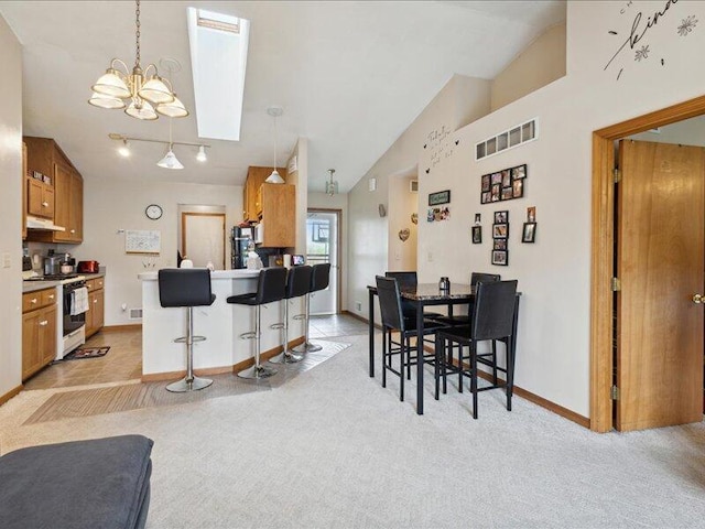 kitchen with white gas stove, light colored carpet, and hanging light fixtures