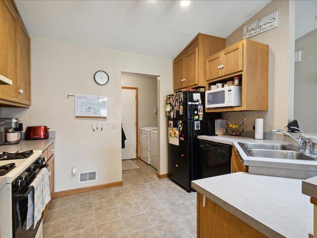 kitchen with black appliances, washing machine and dryer, sink, and vaulted ceiling