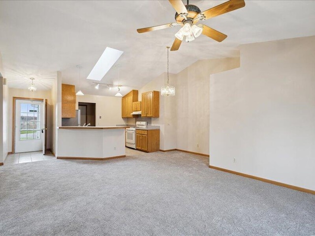 unfurnished living room with ceiling fan with notable chandelier, lofted ceiling with skylight, and light carpet