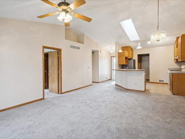 unfurnished living room featuring a skylight, light carpet, ceiling fan, and high vaulted ceiling