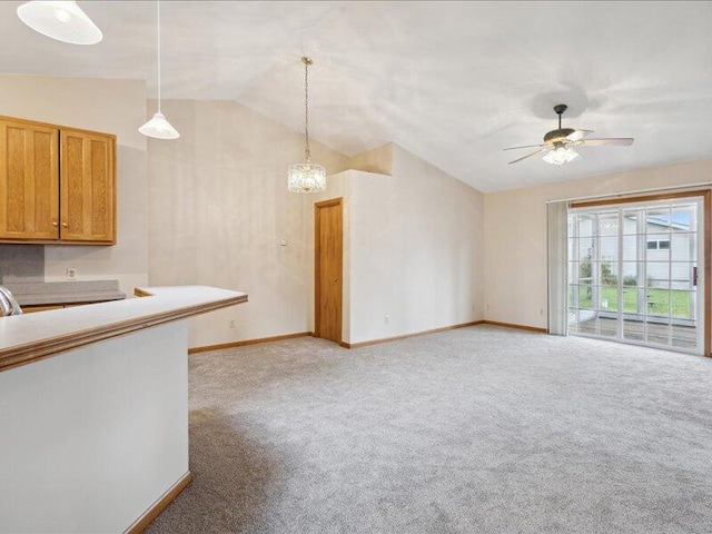 unfurnished living room with ceiling fan with notable chandelier, light colored carpet, and vaulted ceiling