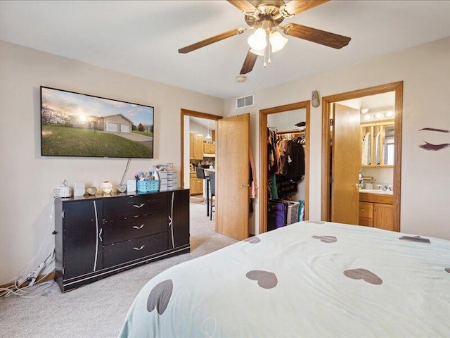 bedroom with light carpet, ensuite bath, ceiling fan, a spacious closet, and a closet