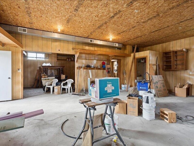 misc room featuring concrete flooring and wooden walls