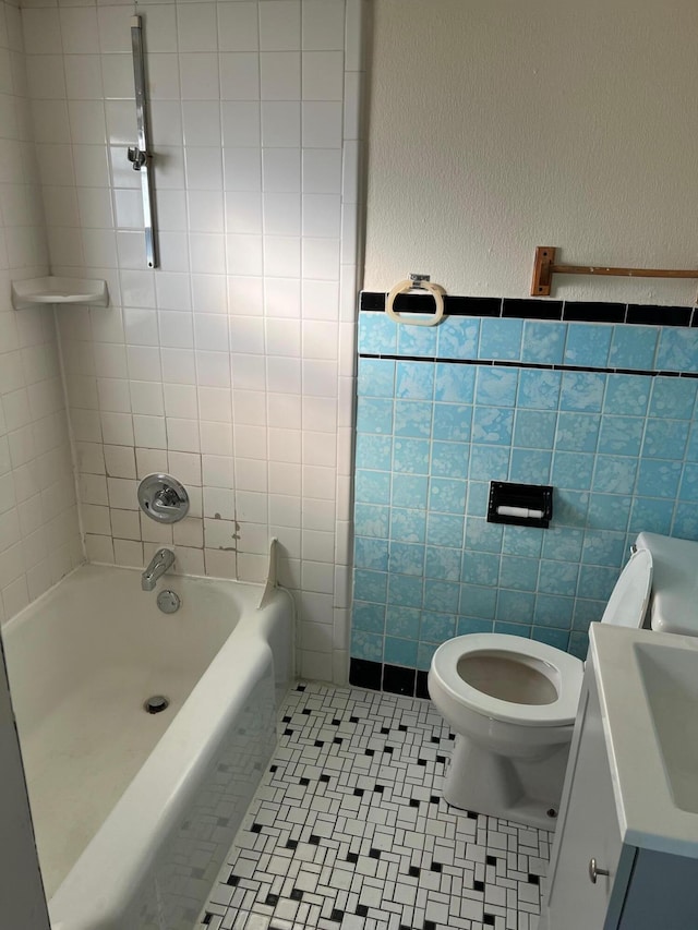 bathroom featuring tile patterned floors, tiled shower / bath combo, toilet, and tile walls