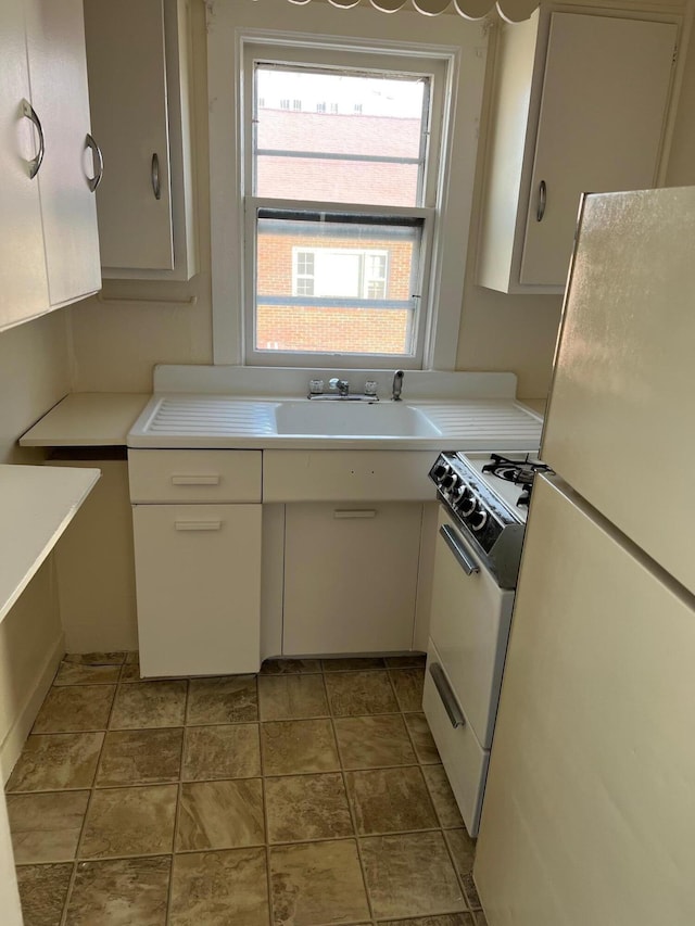 kitchen with sink, white cabinets, and white appliances