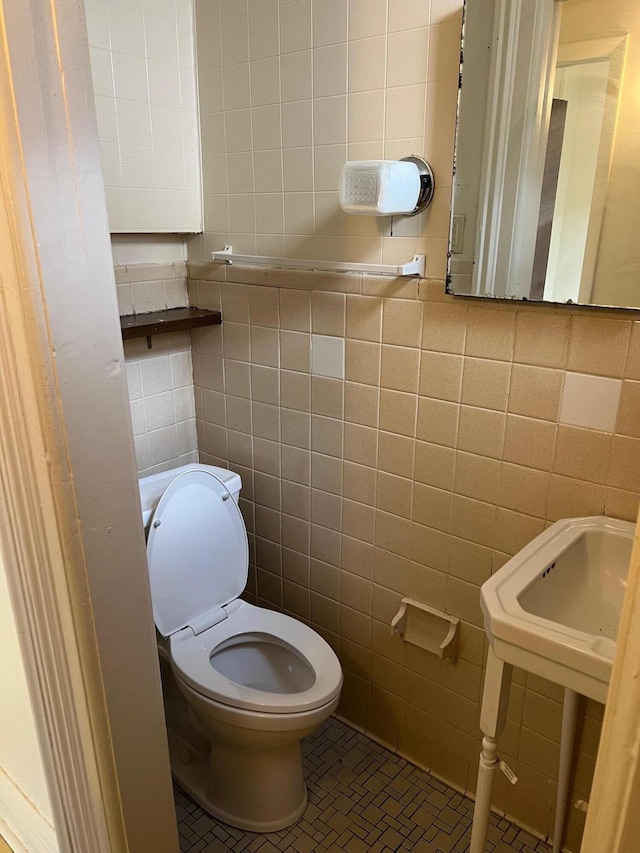 bathroom featuring tile patterned flooring, tile walls, and toilet