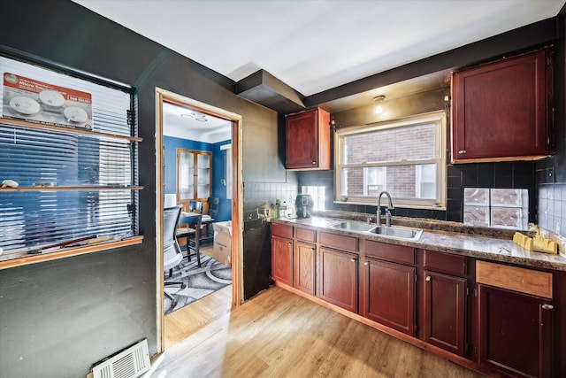 kitchen featuring backsplash, sink, dark stone counters, and light hardwood / wood-style flooring