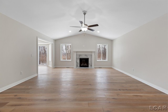 unfurnished living room featuring ceiling fan, vaulted ceiling, light wood-type flooring, and a fireplace