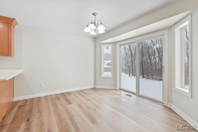 unfurnished dining area with light hardwood / wood-style floors and a notable chandelier