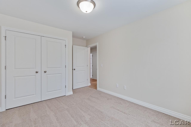 unfurnished bedroom with light carpet and a closet