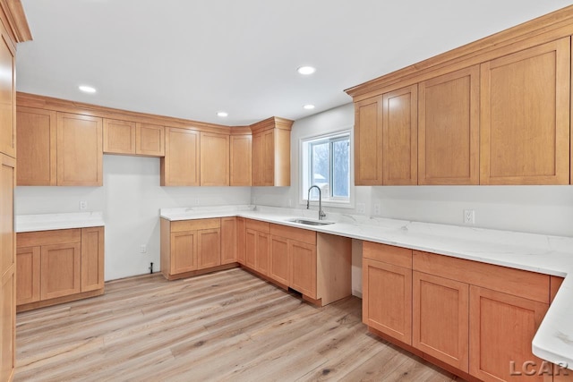 kitchen with light stone countertops, sink, and light hardwood / wood-style flooring