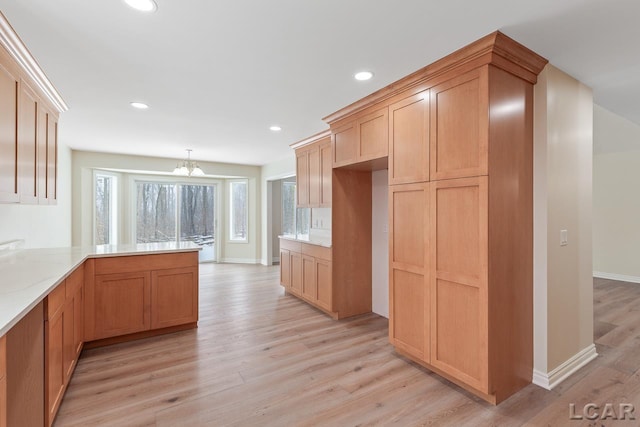 kitchen featuring kitchen peninsula, pendant lighting, an inviting chandelier, and light hardwood / wood-style flooring