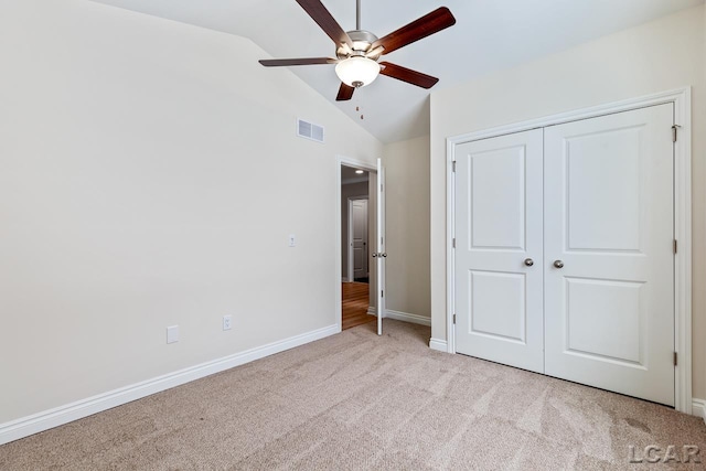 unfurnished bedroom with ceiling fan, light colored carpet, a closet, and lofted ceiling