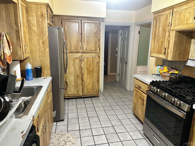 kitchen with tasteful backsplash, sink, light tile patterned floors, and appliances with stainless steel finishes