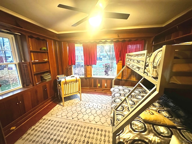 interior space with wood walls, plenty of natural light, ceiling fan, and crown molding