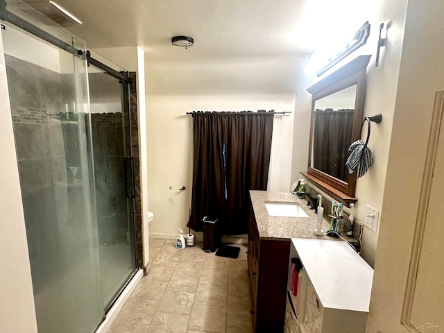 bathroom with vanity, toilet, and a shower with door