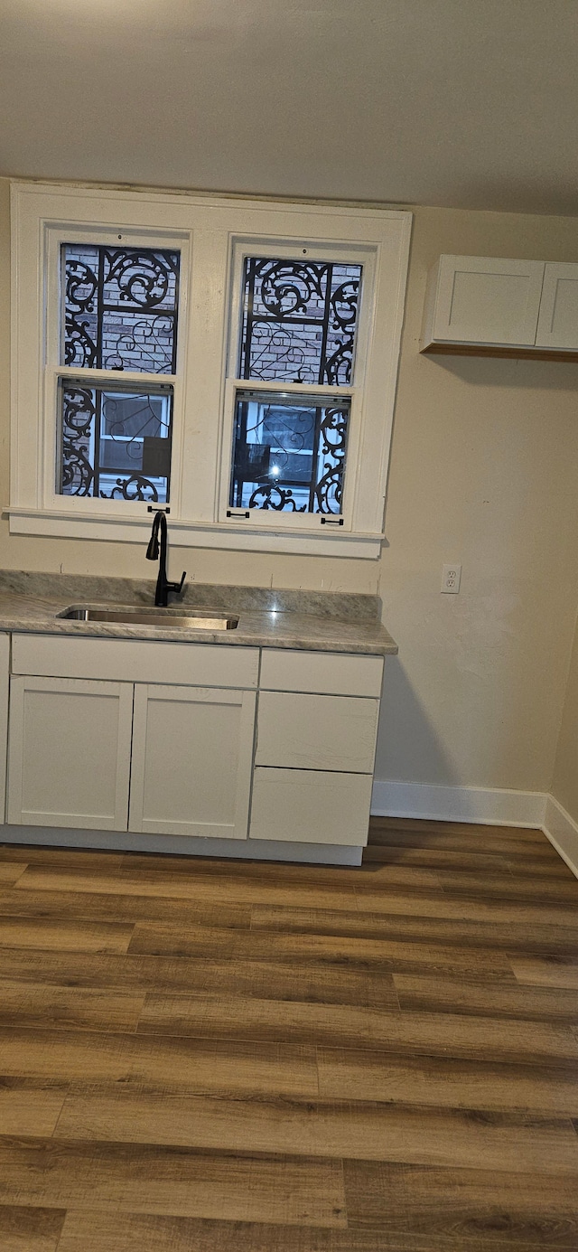 bar featuring dark hardwood / wood-style floors, white cabinetry, and sink