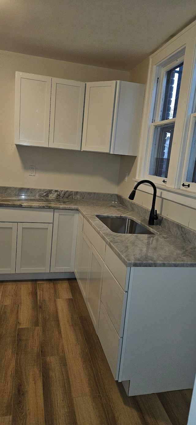 kitchen with dark hardwood / wood-style flooring, white cabinetry, and sink