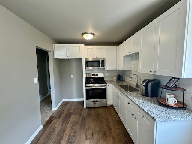 kitchen featuring light stone countertops, appliances with stainless steel finishes, dark hardwood / wood-style flooring, sink, and white cabinets