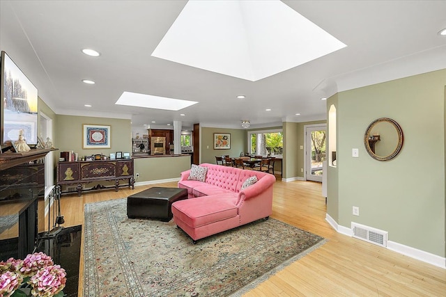 living room with a skylight, ornamental molding, and hardwood / wood-style flooring