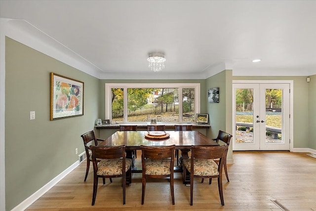 dining area with a notable chandelier, plenty of natural light, french doors, and light hardwood / wood-style flooring