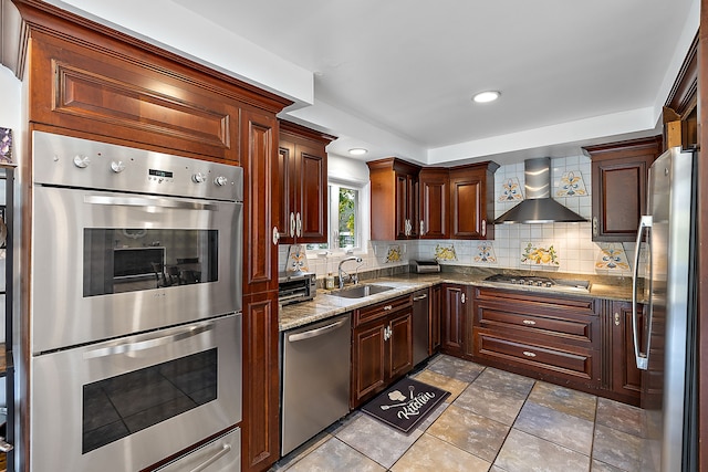 kitchen with backsplash, wall chimney range hood, sink, light stone counters, and stainless steel appliances