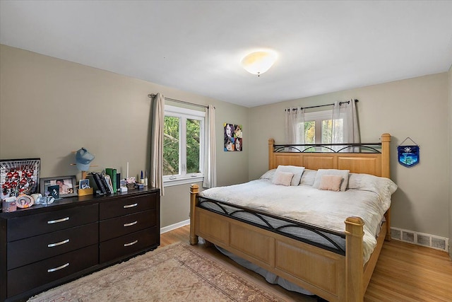 bedroom featuring light wood-type flooring, multiple windows, visible vents, and baseboards