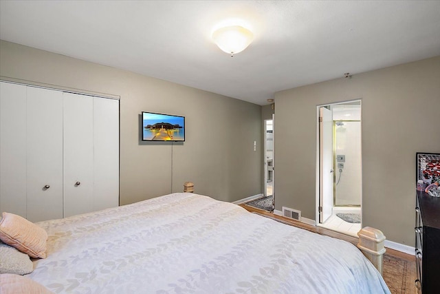 bedroom featuring hardwood / wood-style floors, ensuite bath, and a closet