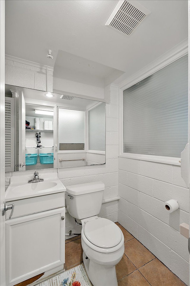 half bathroom with toilet, vanity, visible vents, and tile patterned floors