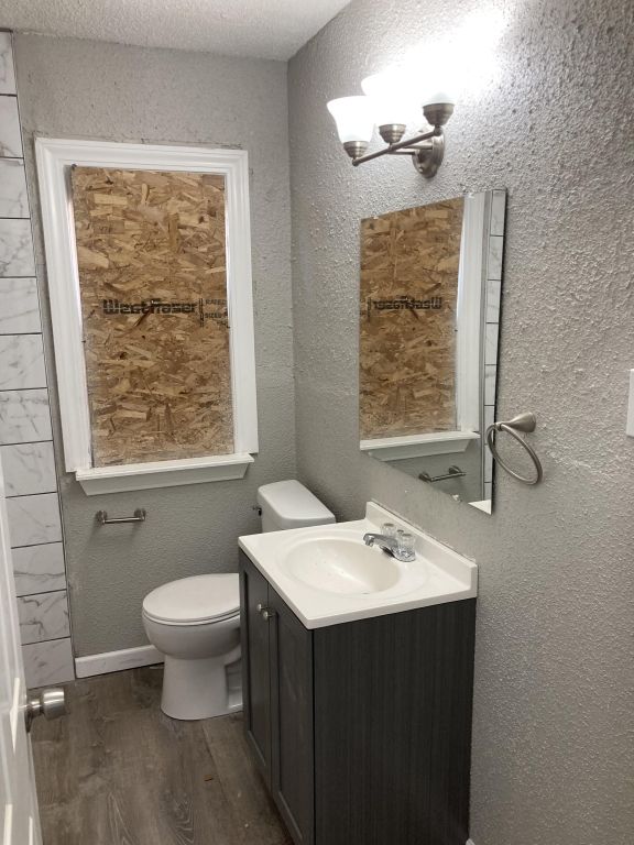 bathroom with vanity, wood-type flooring, a textured ceiling, and toilet