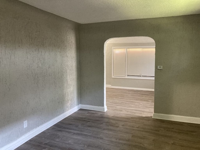 empty room featuring a textured ceiling and dark wood-type flooring