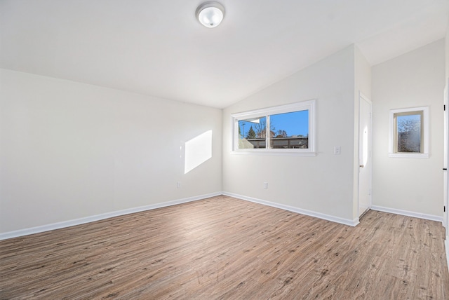 spare room with light hardwood / wood-style floors and lofted ceiling