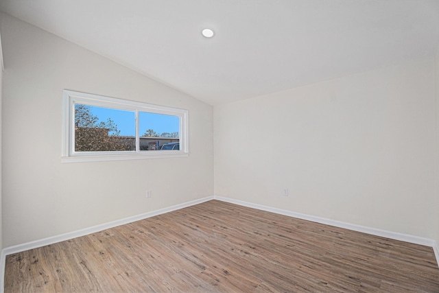 unfurnished room with hardwood / wood-style floors and vaulted ceiling