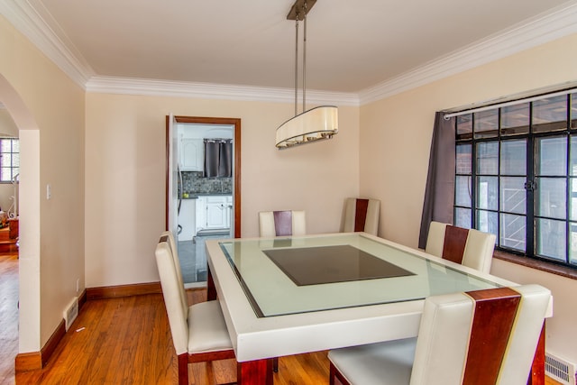 dining area featuring wood-type flooring and crown molding