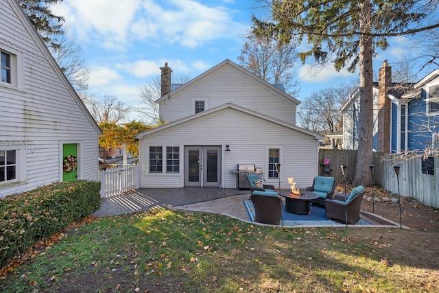 back of property featuring a fire pit, a patio area, a lawn, and french doors