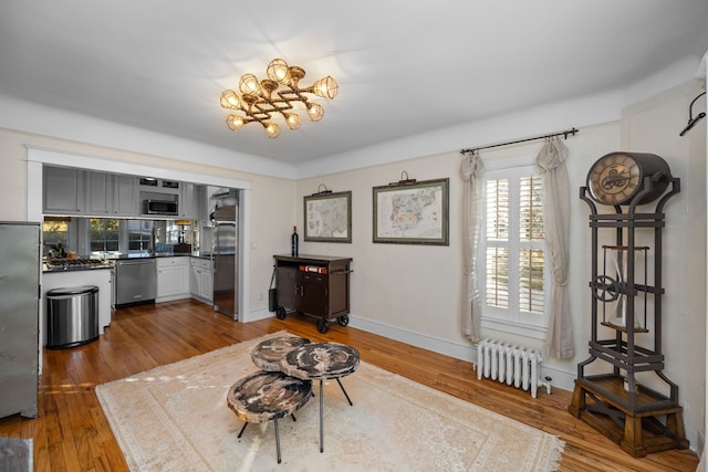 interior space with radiator heating unit, wood-type flooring, and a notable chandelier