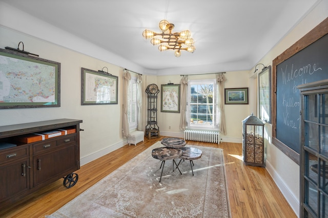 sitting room with a chandelier, radiator heating unit, and light hardwood / wood-style floors