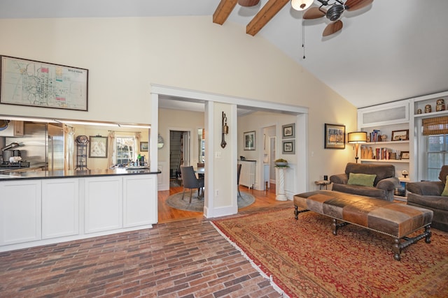 living room with beamed ceiling, ceiling fan, and high vaulted ceiling