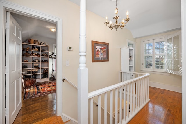 corridor featuring a chandelier, wood-type flooring, and vaulted ceiling