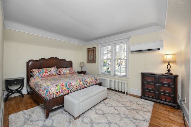 bedroom featuring a wall unit AC, wood-type flooring, and radiator