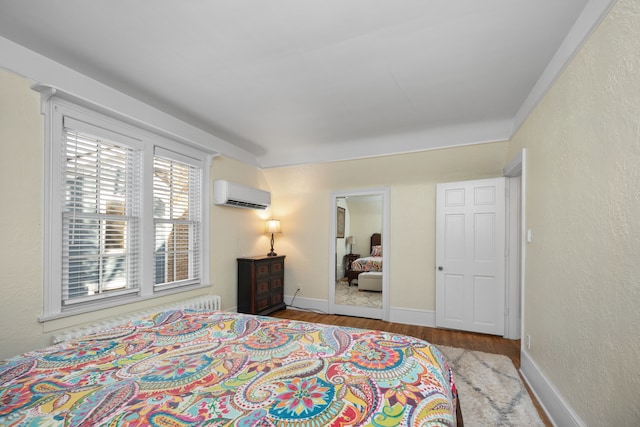 bedroom with a wall mounted AC and light hardwood / wood-style floors